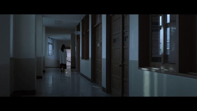 Woman walking down a dimly lit hallway
