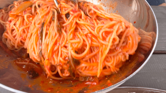 Spicy Korean bibim noodles being mixed in a bowl