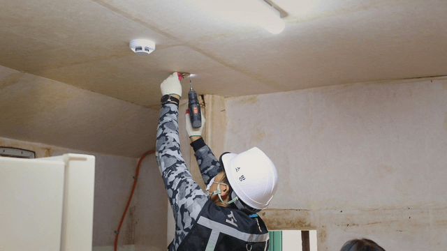 Worker installing a smoke detector indoors