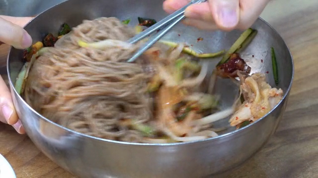 Mixing Korean buckwheat noodles in a bowl