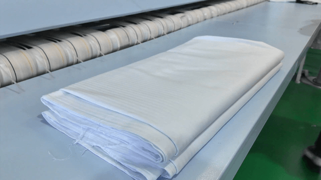 Neatly folded white sheets in laundry factory