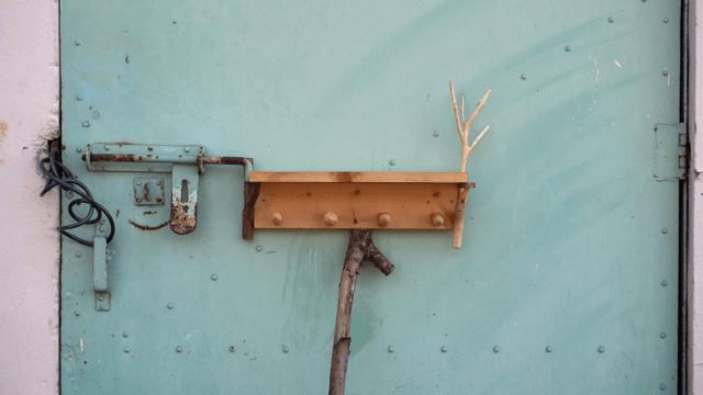Wooden shelf with branches attached to a metal door