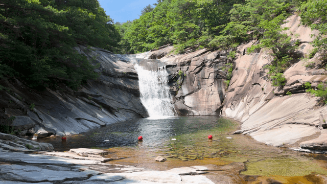 Waterfall dropping into clear rock valley pool