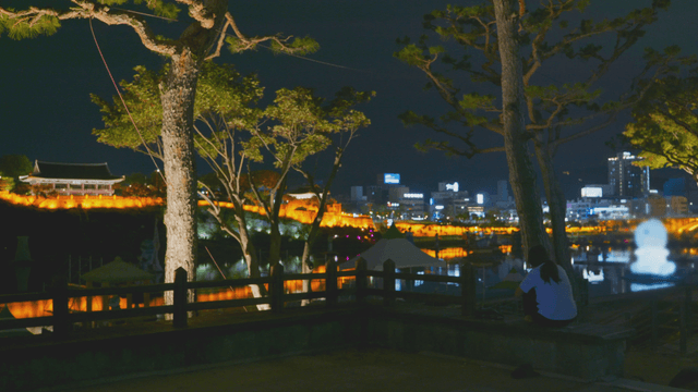 Night view of the city with a traditional pavilion and a resting person
