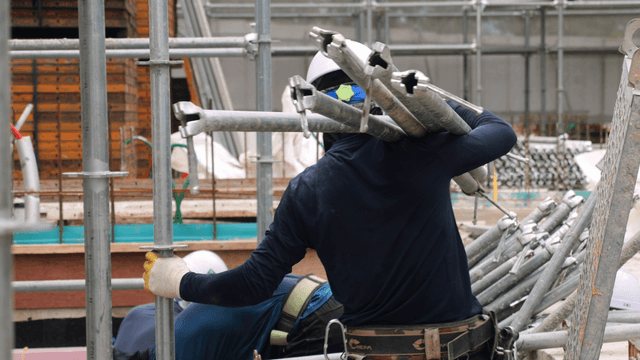 Construction workers carrying metal pipes
