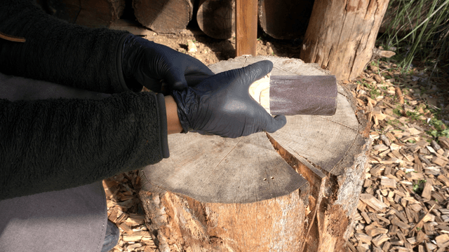 Sanding wooden piece holes on an outdoor workbench