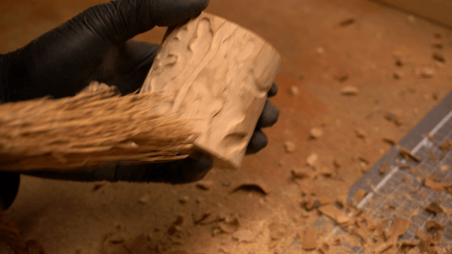 Artisan brushing dust off wooden piece in workshop
