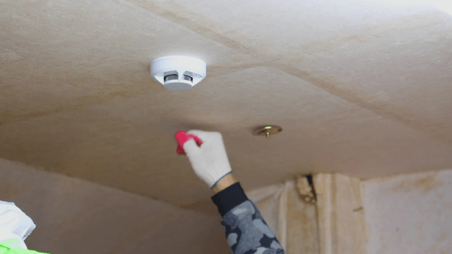 Person installing a smoke detector on the ceiling