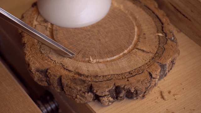 Woodcraft artisan carving a wooden piece with a chisel