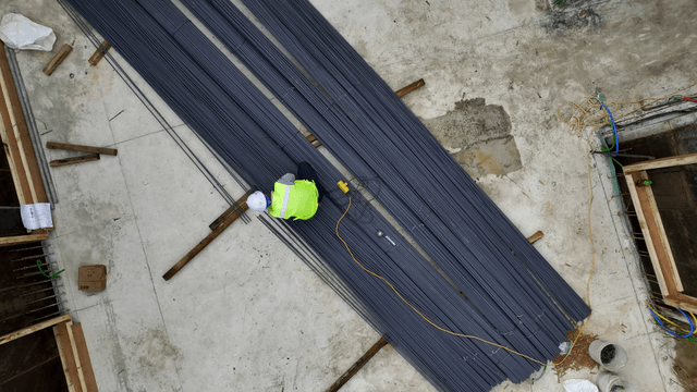 Construction workers handling steel rods