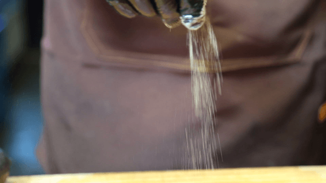 Chef sprinkling powder on a cutting board