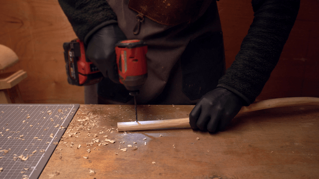 Person drilling a wooden piece on a table