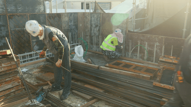 Construction workers handling steel rods