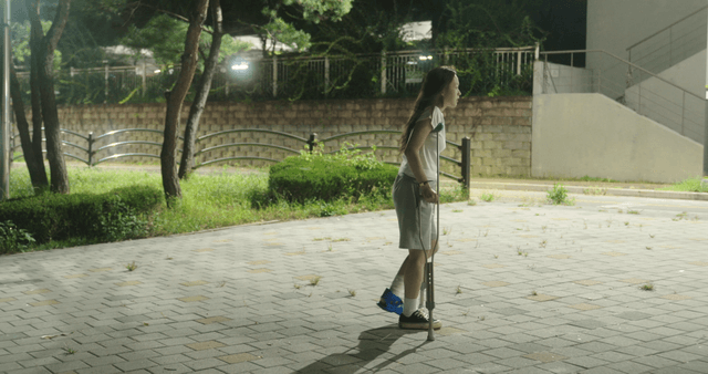 Woman with crutches walking at night