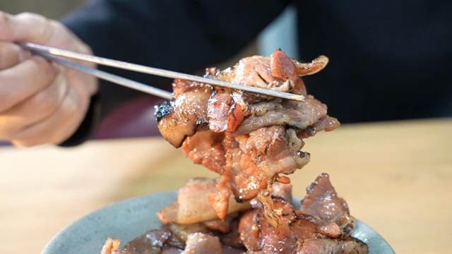 Grilled pork being picked up with chopsticks