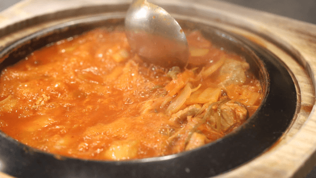 Hot kimchi stew stirred with ladle