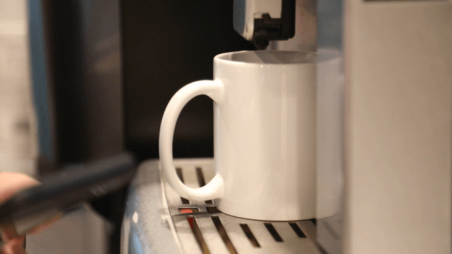 Coffee machine brewing into a white mug