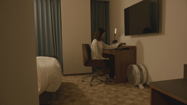 Woman sitting at her hotel room desk making a phone call