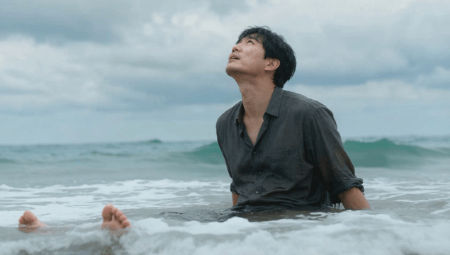 바다에 앉아 위를 바라보는 남자