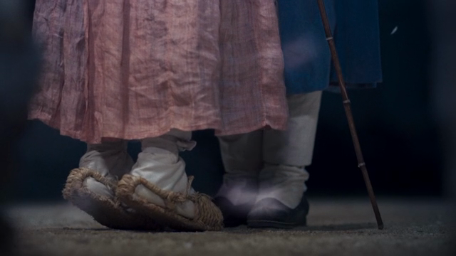 A person in hanbok standing on tiptoe