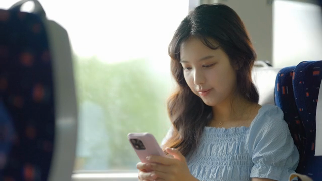 기차에서 스마트폰을 사용하는 여성
