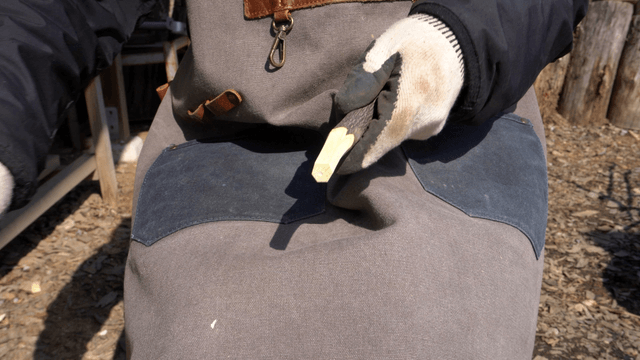 Woodcraft artisan sharpening wood outdoors with a knife