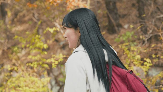 Woman walking with backpack in autumn forest