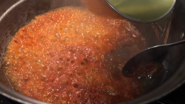 Broth being poured into a pot with spices