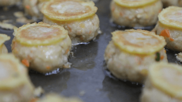 Pan-fried battered meatballs cooking on a hot pan