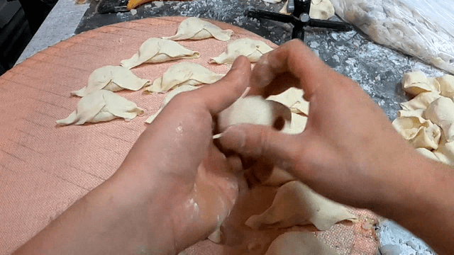 쟁반 위에서 만두 모양을 빠르게 접어내는 손