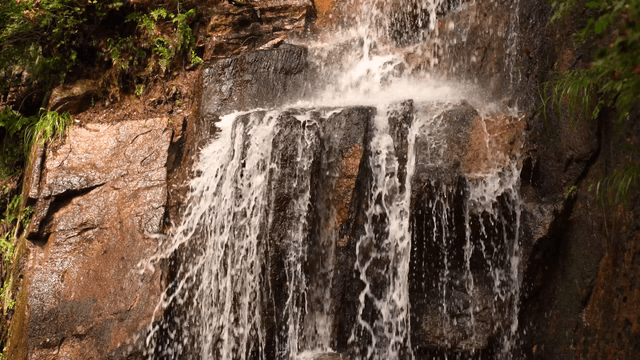 Small waterfall gently flowing down rocky cliff