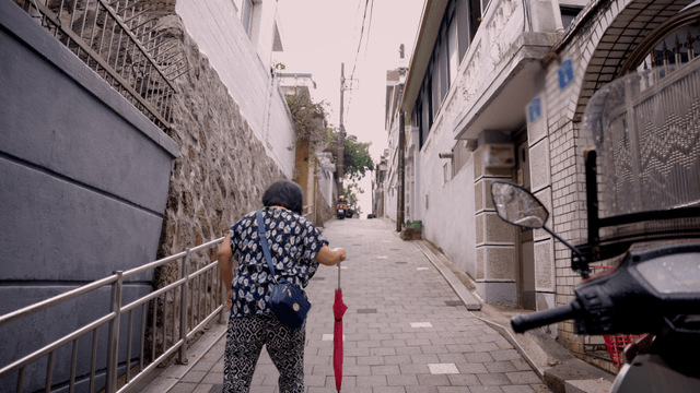 Elderly woman walking up a narrow alley