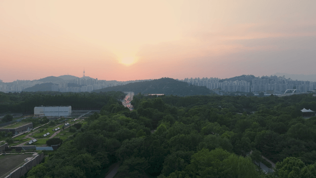 Sunset over dense forest beside downtown Seoul