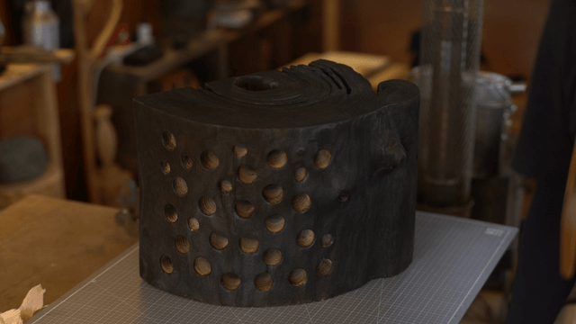 Wooden sculpture with holes on workbench in cozy workshop