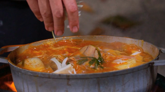 Adding onions to the stew boiling in the pot