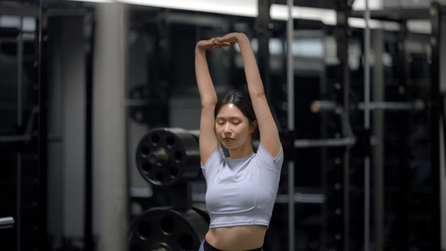 Stretching arm extended by young woman in gym