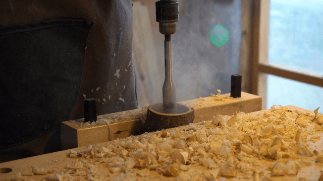 Woodworking drill operation with smoke in workshop