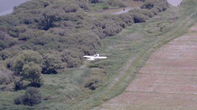 A small plane flying over a scenic park