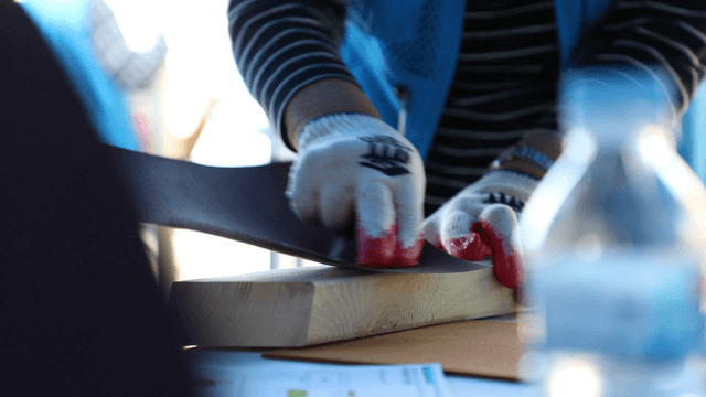 Person sanding a wooden plank with care