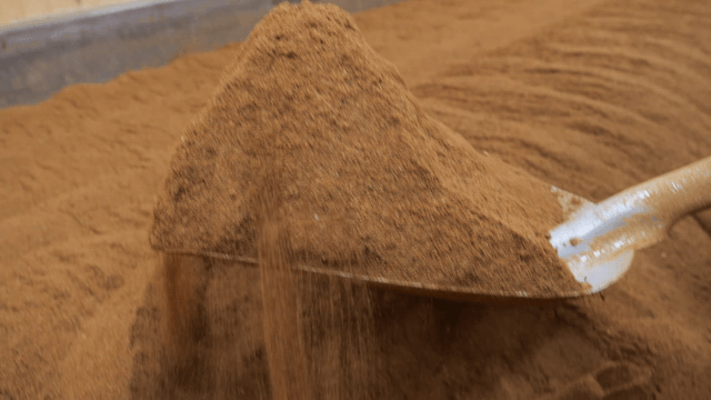 Shovel scooping dense brown soil