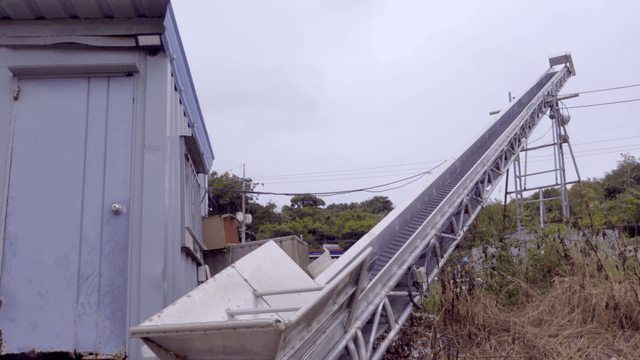 야외 작업장에 설치된 경사 컨베이어 벨트