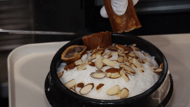 Shaved ice in earthen bowl with almond and red bean bread garnish