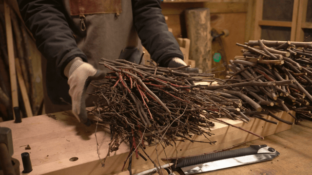 Artisan organizing a pile of wooden branches on workbench