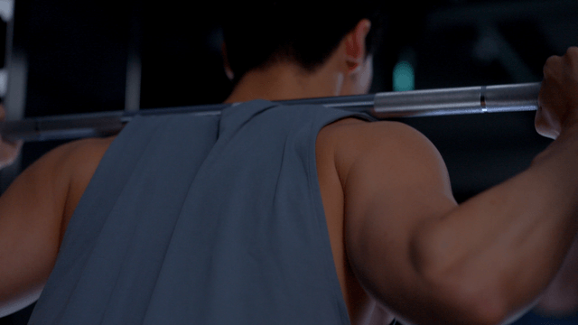 Man performing squat with weighted bar on shoulders