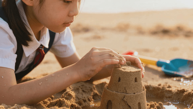 Girl building sandcastle on beach