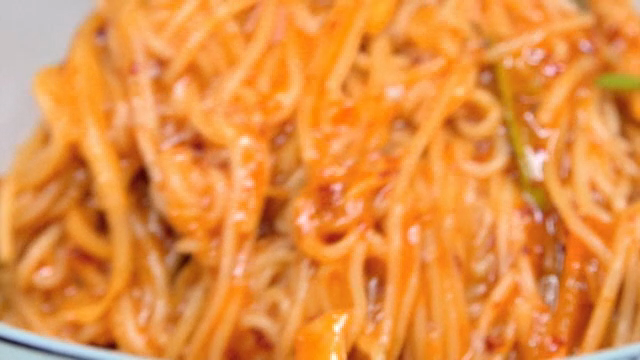 Spicy noodles being mixed in a bowl