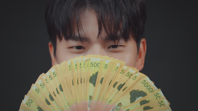A person holding a fan of currency notes