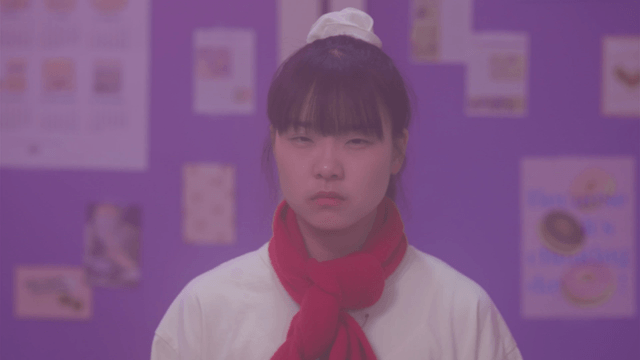 Girl with a red scarf looks straight ahead and spots something