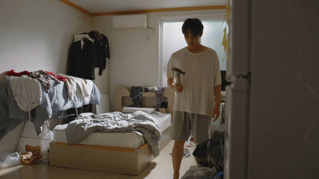 Man in a messy room holding a hammer