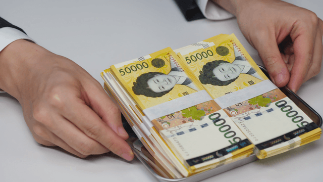 Hand receiving a tray with Korean won bills on it